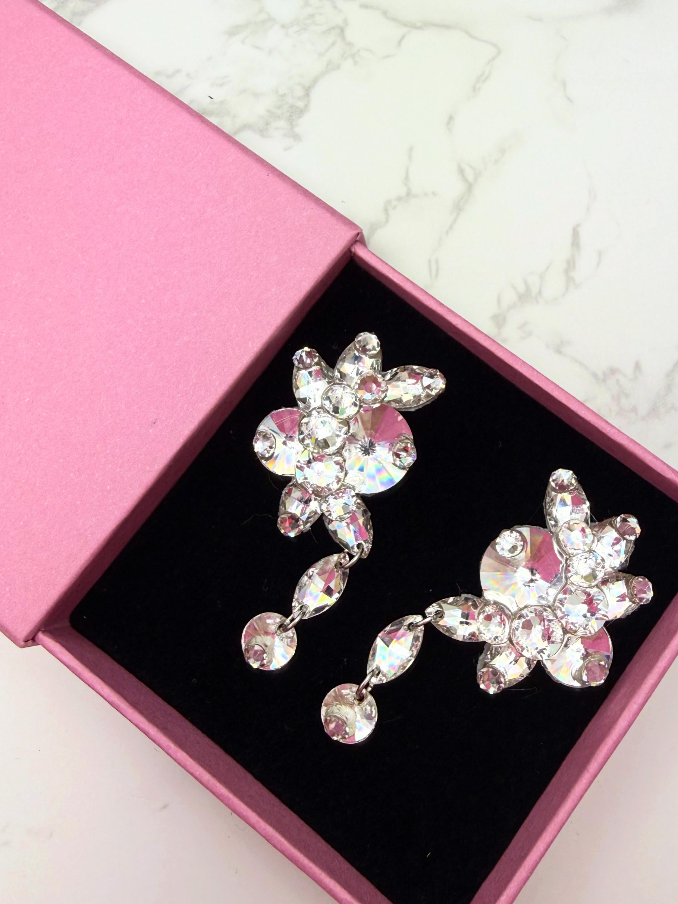 Pair of statement crystal dangle ballroom dance earrings in a pink box on a marble surface